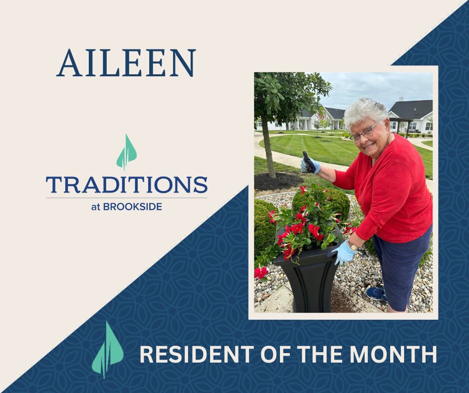 Photo of an elderly woman wearing blue and black gardening gloves holding a thumbs up as she leans against a black pot with red flowers planted in dark soil on a Traditions Management graphic for Resident of the Month