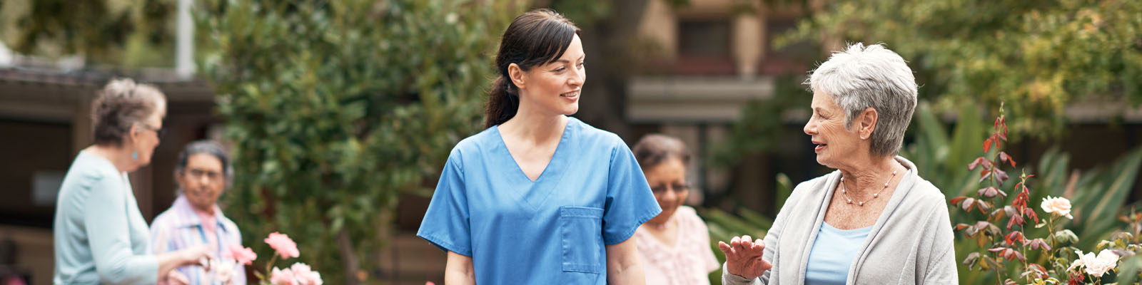 A senior woman walking outdoors with her assisted living nurse